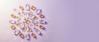Colorful vitamin capsules arranged in circular pattern on soft purple background for health and wellness supplement concepts.