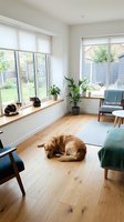 Bright modern living room with pets relaxing on wooden floors, featuring large windows, houseplants, and contemporary furniture in natural light.