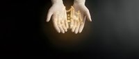 Hands holding glowing golden city skyline with warm light emanating from urban buildings in protective gesture against dark background.