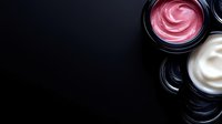 Pink and white luxury cosmetic creams in black jars on dark background, minimal beauty product photography with copy space for skincare branding.