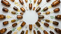 Amber glass bottles with essential oils arranged in circular pattern on white background. Natural aromatherapy and wellness concept for spa treatments.