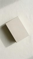 Minimalist beige cardboard box on neutral textured surface with soft natural lighting and subtle shadows for packaging design mockups.