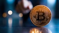 Golden bitcoin coin on reflective surface with blurred blue bokeh background, cryptocurrency concept showing digital money investment and trading.