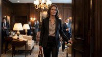 Professional businesswoman in elegant black suit walking through luxury hotel lobby with confident stride and warm smile.