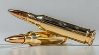 Golden rifle bullets with copper tips on white background, showcasing metallic ammunition with polished brass casings and pointed projectiles for hunting or sport shooting.