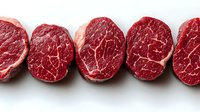 Fresh raw beef tenderloin steaks with marbled texture arranged in row on white background, showing natural meat grain pattern and rich red color.