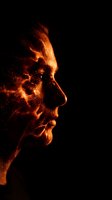 Fiery male face profile with glowing orange flames and sparks dispersing against black background creating dramatic supernatural transformation effect.