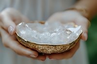 Hands holding coconut shell bowl filled with clear quartz crystals for healing meditation and spiritual wellness practices.