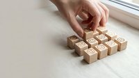 Hand arranging wooden blocks with percentage symbols on light surface near window for business growth and financial planning concepts.