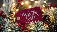 Red winter sale tag on snowy pine branches with pinecones, red berries, and warm bokeh lights for holiday retail promotion.