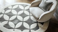 Modern circular pattern area rug in gray and white with geometric overlapping circles design, shown with contemporary beige armchair and decorative pillow.