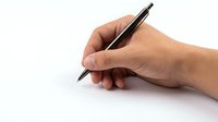 Close-up of a hand holding a black ballpoint pen, ready to write, isolated on a white background for business and education use.