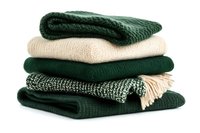 Stack of folded knitted blankets and scarves in green and beige tones isolated on white background.