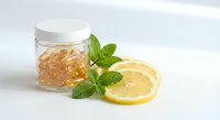 Natural honey in glass jar with fresh mint leaves and lemon slices on white background for healthy lifestyle and organic food concepts.