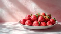 Fresh ripe strawberries arranged on white plate with soft natural light and pink background, suitable for food photography, recipe blogs, and healthy eating content.