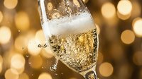 Champagne flute with sparkling wine and bubbles pouring against golden bokeh background, celebration and festive occasion beverage.