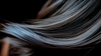 Smooth flowing silver gray hair strands in gentle wave motion against dark background, highlighting natural shine and texture for beauty and haircare concepts.