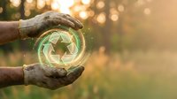 Hands holding glowing green leaf symbol with golden sunset bokeh background, representing environmental protection, sustainability, and eco-friendly energy concepts.