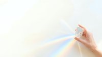 Light refracting through crystal prism held in hand, creating rainbow spectrum on neutral background. Suitable for science, education, and optical concepts.