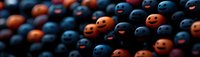 Playful pattern of orange and navy blue smiling spheres arranged in rows creating cheerful mood composition against dark background. Halloween concept.