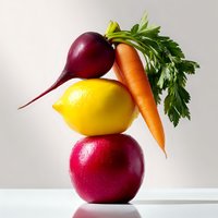 Fresh organic produce stacked creatively with red apple, lemon, beetroot and carrot with green leaves on light background. Healthy eating concept.