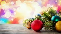 Festive Christmas ornaments and pine branches on wooden surface with colorful bokeh background, perfect for holiday greeting cards.