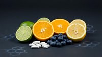 Fresh citrus fruits lime orange lemon with blueberries and vitamin tablets on dark hexagonal background for healthy nutrition and dietary supplements.
