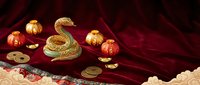 Golden snake figurine with coins and ornaments arranged on luxurious crimson velvet fabric, suitable for wealth, prosperity, and fortune-themed designs.