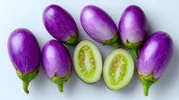 Fresh purple eggplants arranged in row with two halved pieces showing green flesh inside on white background, organic vegetables for healthy cooking.