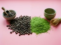 Coffee beans and vibrant green matcha powder side by side on pink background with mortar, bowl, and bamboo whisk for wellness content.