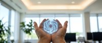 Hands cupping glowing digital spiral hologram in modern office space representing innovation, technology solutions and business transformation concepts.