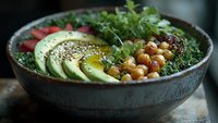 Nutritious breakfast bowl with sliced avocado, chickpeas, fresh herbs, and soft-boiled egg in ceramic dish, showcasing healthy plant-based meal options.