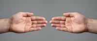 Two open male hands reaching toward each other on a gray background, symbolizing connection, help, cooperation, and partnership.