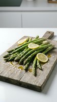 Fresh green asparagus spears with lemon slices on rustic wooden cutting board. Healthy organic vegetables prepared for cooking in modern kitchen.
