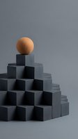 Wooden sphere balanced on top of stacked dark concrete cubes against neutral background, representing leadership, success, achievement, and business growth concepts for corporate design.