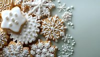 Delicate snowflake sugar cookies decorated with white royal icing on mint green background. Festive winter treats with intricate frost patterns and pearl details.