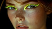 Young Caucasian woman with freckles wearing vibrant neon green artistic eye makeup and eyeliner for beauty fashion editorial or creative portrait photography.