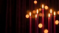 Red candles burning with warm golden flames creating romantic atmosphere with soft bokeh lights in dark background for celebration and relaxation.