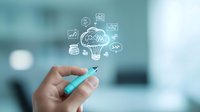 Hand holding blue marker pointing at light bulb with business icons, representing creative thinking and innovation in corporate environment.