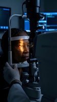 African American woman receiving comprehensive eye examination using advanced slit lamp microscope in modern ophthalmology clinic for vision health assessment.