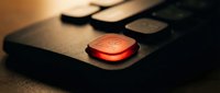 Red emergency stop button on industrial control panel with dramatic lighting for safety and manufacturing concepts.