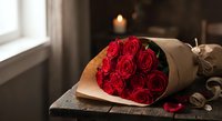 Elegant red roses bouquet wrapped in kraft paper on wooden surface with warm candlelight creating romantic atmosphere for Valentine's Day or anniversary celebration.