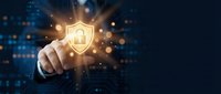 Businessman touching glowing shield icon with padlock symbol representing cybersecurity protection and data privacy in digital technology environment.