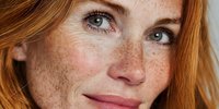 Close-up portrait of young Caucasian woman with freckles and red hair smiling naturally. Fresh skincare and beauty concept for cosmetics advertising.