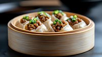Steamed dumplings filled with minced meat and topped with fresh green onions served in traditional bamboo steamer basket on dark background.