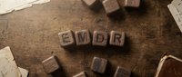 Wooden letter blocks spelling EMDR on rustic wood surface with scattered alphabet cubes for therapy and mental health concepts.