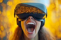 Young woman experiencing virtual reality with open mouth expression of joy and amazement against golden bokeh background. VR headset reflects glowing lights.