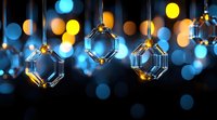 Crystal glass octagonal pendants hanging against blurred bokeh lights in blue and gold colors creating magical festive atmosphere for holiday decor.