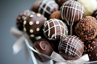 Assorted chocolate truffles and bonbons with white drizzle and cocoa coating in decorative arrangement, perfect for confectionery, bakery, dessert, and gourmet food marketing.
