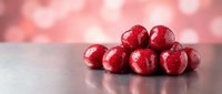 Fresh red cranberries arranged on reflective surface with soft pink bokeh background for holiday cooking and festive seasonal decorations.